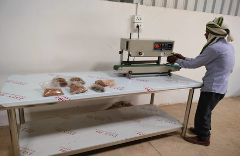 Worker sealing packaged products with a heat sealing machine